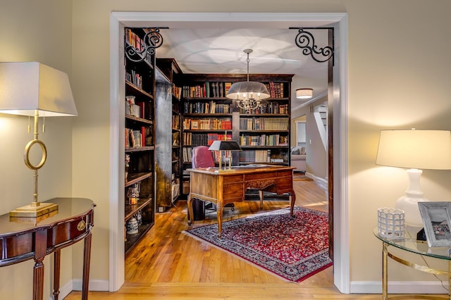 office space with baseboards, an inviting chandelier, and wood finished floors