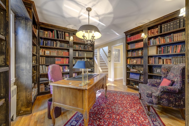 office space featuring a notable chandelier, radiator heating unit, wood finished floors, and ornamental molding