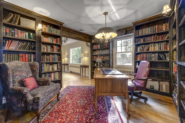 home office with visible vents, radiator, an inviting chandelier, and wood finished floors