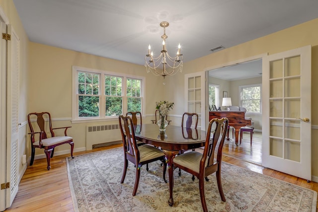 dining room with visible vents, radiator, baseboards, light wood-style flooring, and a notable chandelier