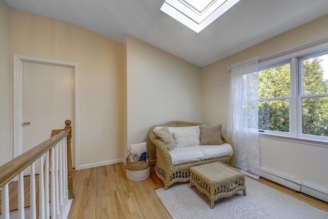 living area featuring lofted ceiling with skylight, baseboards, light wood-style floors, and a baseboard radiator