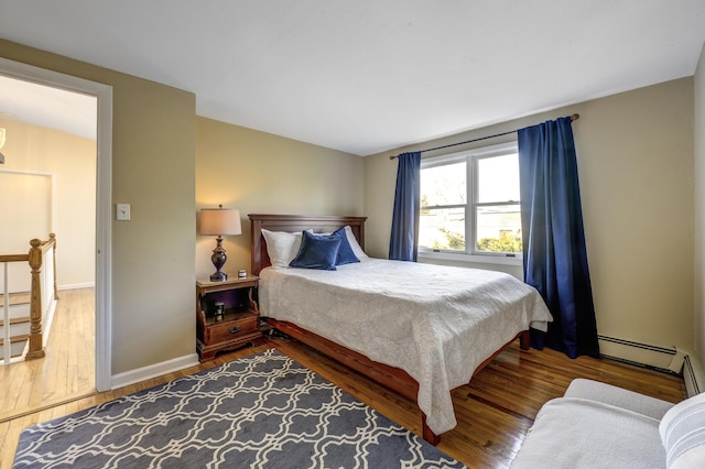 bedroom with wood-type flooring, baseboards, and baseboard heating