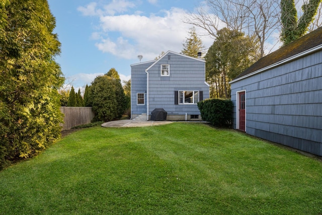 rear view of property with fence, a patio area, and a lawn