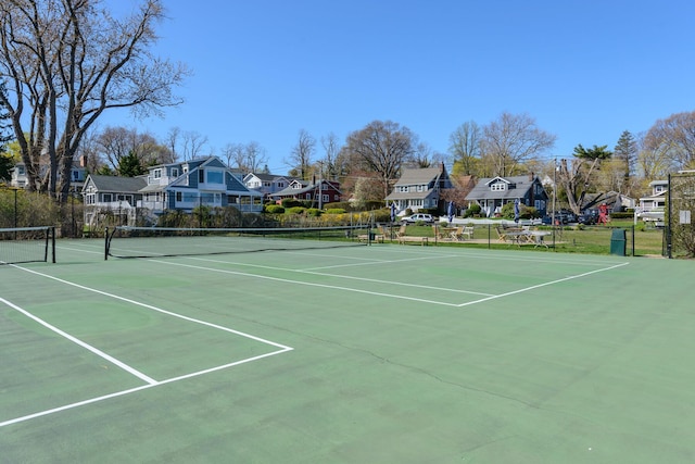 view of tennis court featuring a residential view and fence