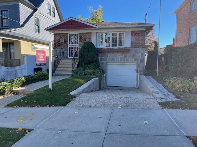 view of front of house featuring concrete driveway, stone siding, an attached garage, fence, and brick siding