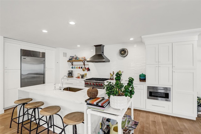 12 Bob White Dr, Water Mill, NY 11976 - kitchen featuring premium appliances, light wood-style floors, white cabinetry, a sink, and wall chimney range hood