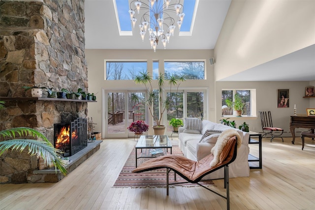 living room with a stone fireplace, a skylight, a high ceiling, and hardwood / wood-style floors