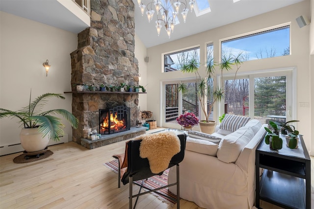 living room featuring a stone fireplace, high vaulted ceiling, and wood finished floors