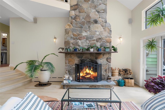 living area featuring beam ceiling, a fireplace, a towering ceiling, wood finished floors, and a baseboard radiator