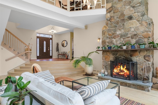 living room with stairway, wood finished floors, a high ceiling, a fireplace, and a notable chandelier