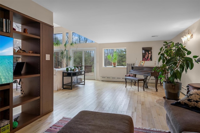 living room featuring a baseboard heating unit, light wood-style floors, and visible vents