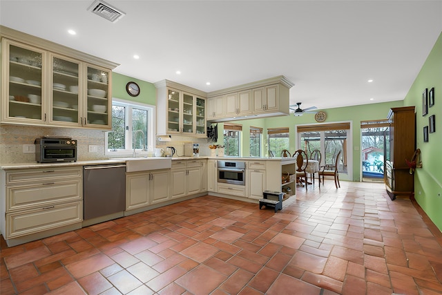 kitchen with visible vents, a sink, cream cabinets, appliances with stainless steel finishes, and a peninsula