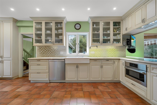 kitchen featuring a sink, recessed lighting, stainless steel appliances, light countertops, and glass insert cabinets