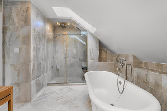 full bath with tile walls, vaulted ceiling with skylight, a shower stall, and a freestanding bath