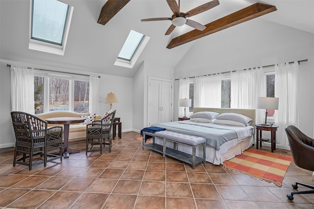 tiled bedroom with a skylight, baseboards, beamed ceiling, and high vaulted ceiling