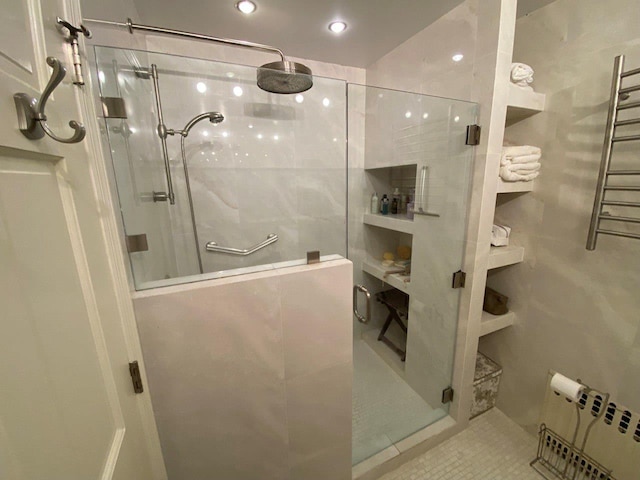 full bathroom featuring tile patterned floors, radiator, tile walls, and a shower stall