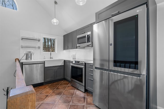 kitchen featuring gray cabinetry, dark tile patterned floors, a sink, backsplash, and appliances with stainless steel finishes