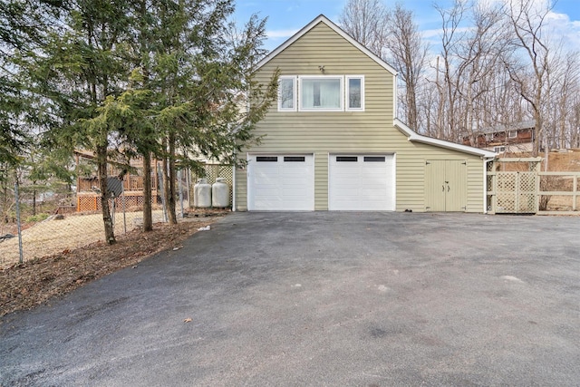 view of side of home with an attached garage, fence, and driveway