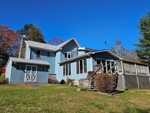 rear view of property with a chimney, a deck, a lawn, and an outdoor structure