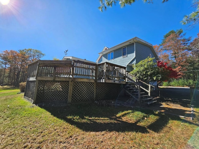 back of property featuring stairs, a deck, and a lawn