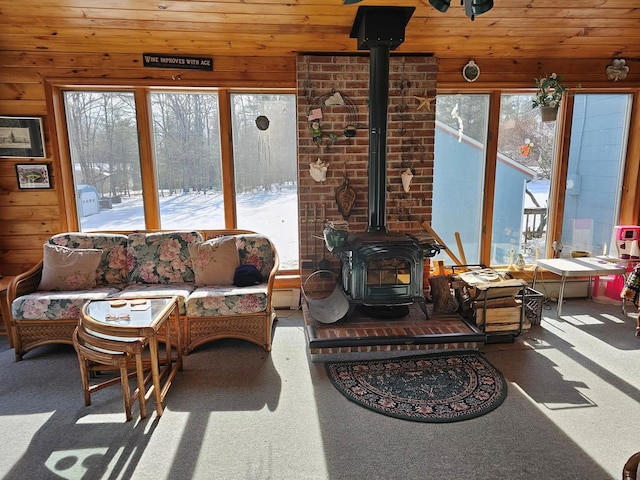 sunroom featuring wood ceiling and a wood stove