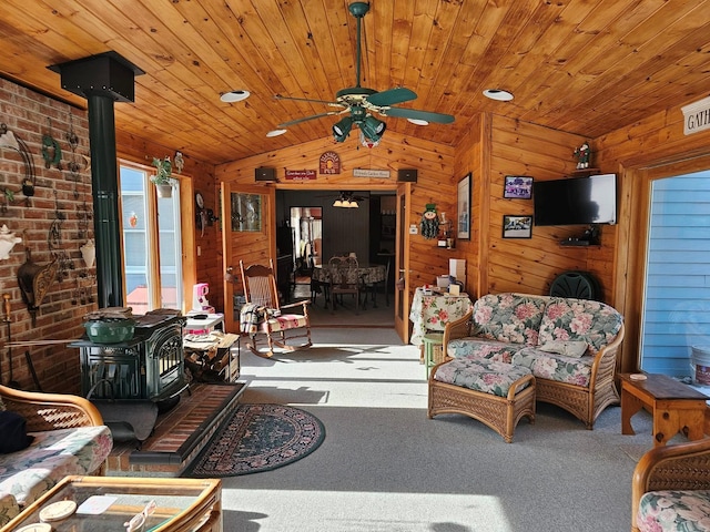 carpeted living room featuring lofted ceiling, wood ceiling, wood walls, and a wood stove