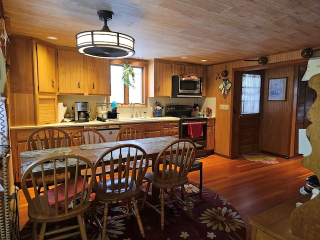 kitchen featuring light wood finished floors, wood ceiling, stainless steel appliances, and a sink