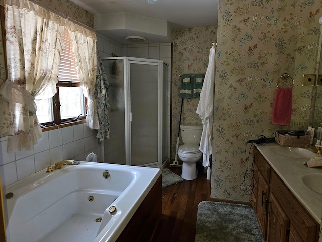 bathroom featuring toilet, a stall shower, a sink, a jetted tub, and wallpapered walls