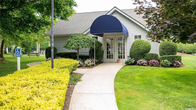 view of front of house featuring roof with shingles, a front yard, and french doors