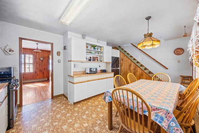 dining area with a baseboard heating unit, stairway, and wooden walls