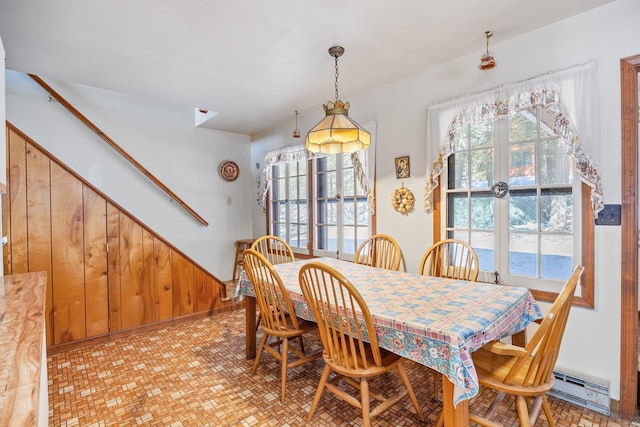 dining space with a baseboard radiator and wooden walls