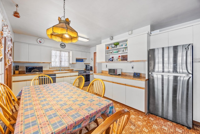 kitchen featuring electric range, white cabinets, freestanding refrigerator, light countertops, and a sink