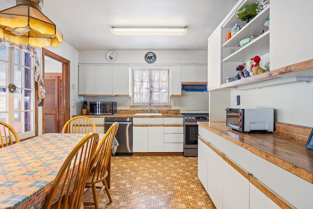 kitchen with a toaster, open shelves, stainless steel appliances, white cabinetry, and a sink