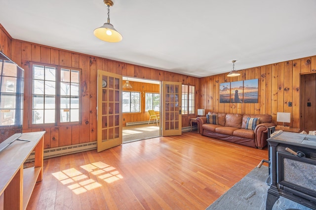 living area with baseboard heating, a baseboard radiator, light wood-style flooring, and wooden walls