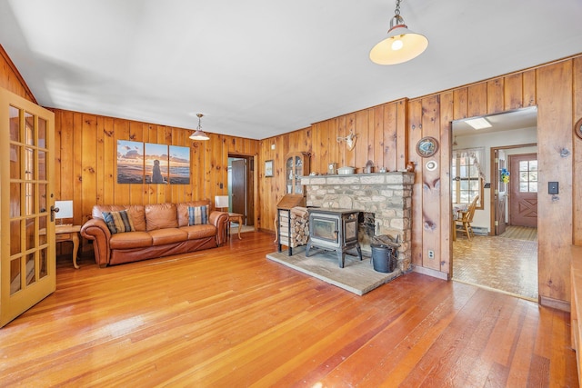 living area featuring light wood-style flooring, a wood stove, and wooden walls