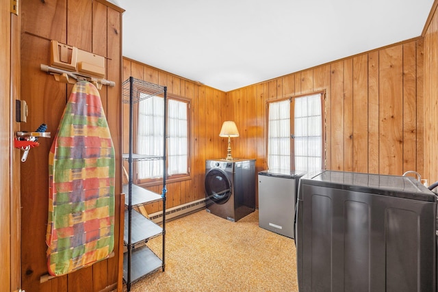 washroom featuring laundry area, washing machine and dryer, wooden walls, and a baseboard heating unit