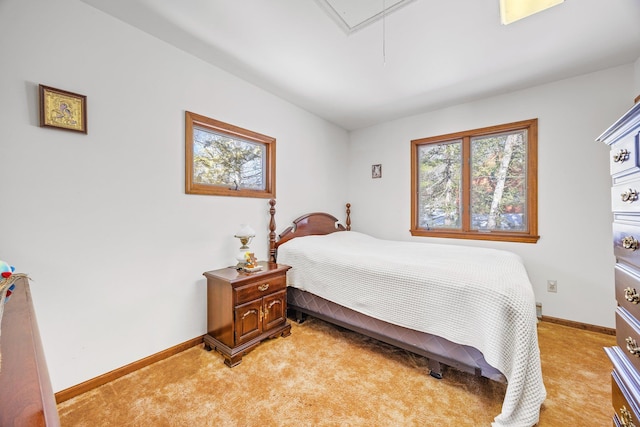 bedroom featuring attic access, light colored carpet, and baseboards