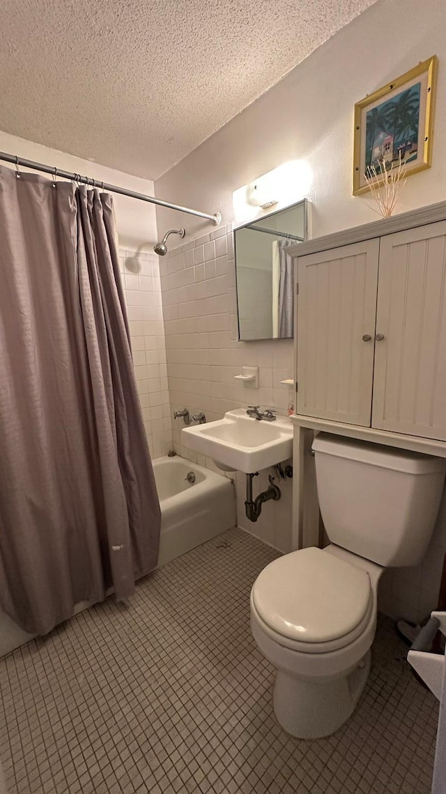 full bathroom featuring shower / bath combination with curtain, toilet, a sink, a textured ceiling, and tile patterned floors