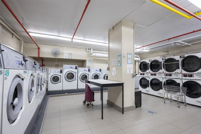 shared laundry area with stacked washing maching and dryer, washing machine and clothes dryer, and tile patterned floors