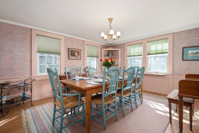 dining space with ornamental molding, a healthy amount of sunlight, a wainscoted wall, and wallpapered walls