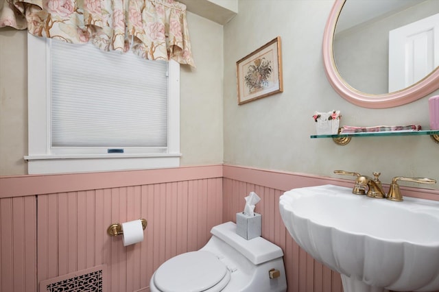 bathroom featuring wainscoting, a sink, and toilet