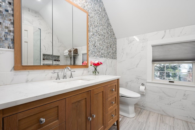 full bath featuring toilet, vanity, tile walls, vaulted ceiling, and a marble finish shower