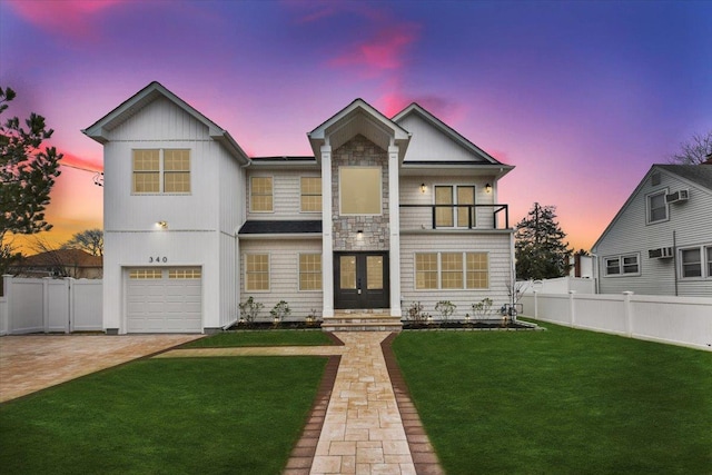 view of front of house featuring decorative driveway, french doors, fence, a balcony, and a front lawn