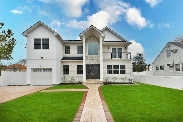 view of front of property with an attached garage, a balcony, fence, decorative driveway, and a front yard