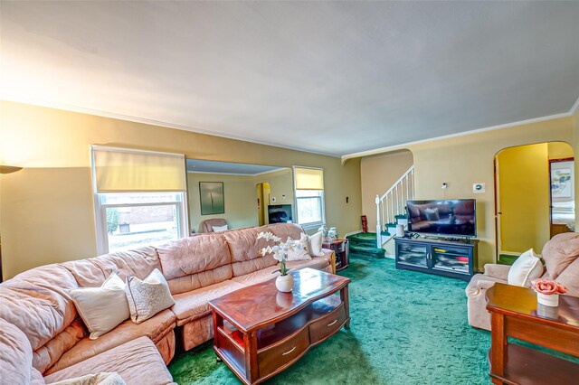 carpeted living area featuring stairs, arched walkways, and crown molding