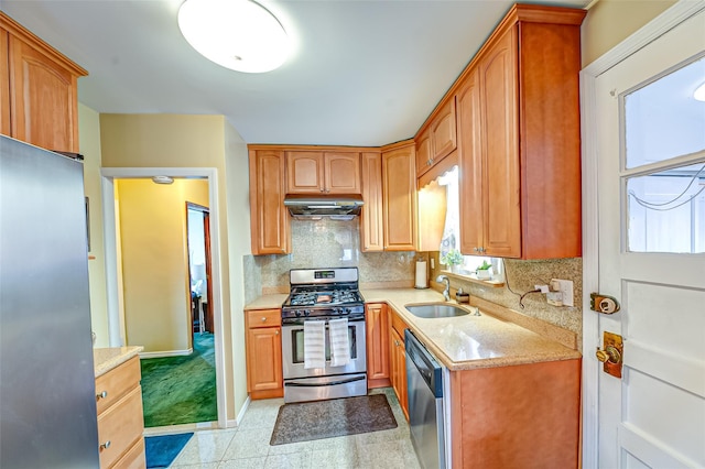 kitchen with light stone counters, stainless steel appliances, backsplash, a sink, and under cabinet range hood