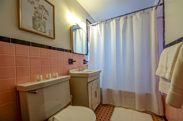 full bathroom featuring a wainscoted wall, vanity, toilet, and tile walls