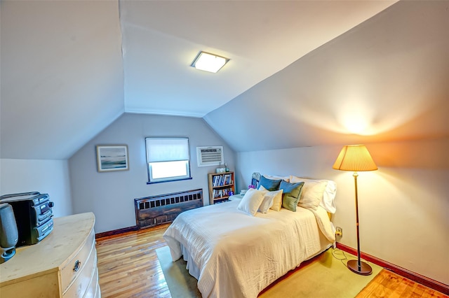 bedroom featuring lofted ceiling, an AC wall unit, light wood finished floors, and heating unit