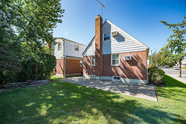 rear view of property featuring a yard, a patio area, a chimney, and brick siding