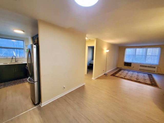 interior space featuring light wood-type flooring, baseboards, a sink, and radiator heating unit